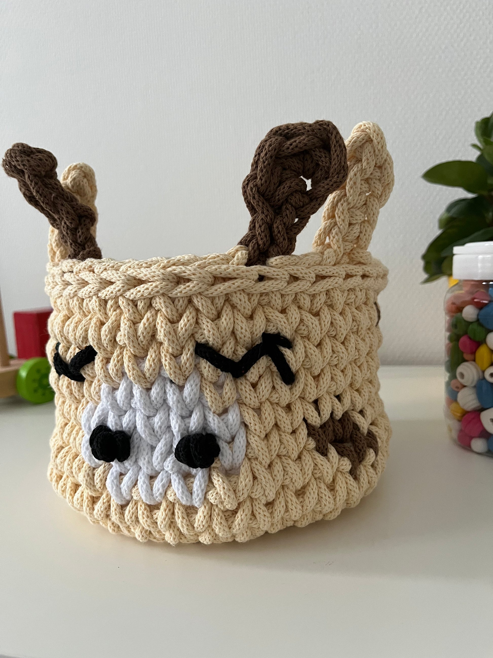Handmade giraffe basket made from recycled cotton cord for toy storage in kids room.