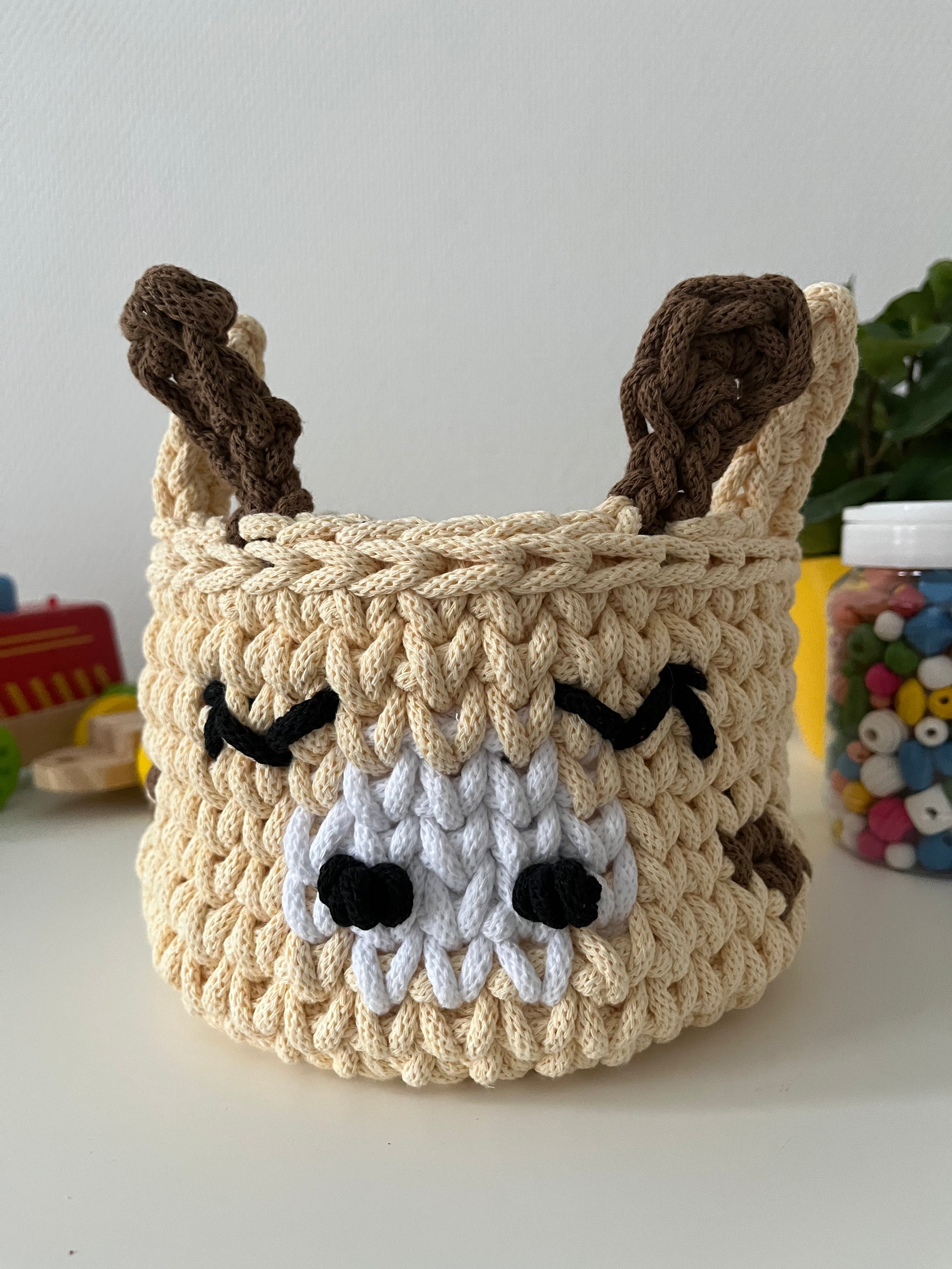 Handmade giraffe basket made from recycled cotton cord for toy storage in kids room.