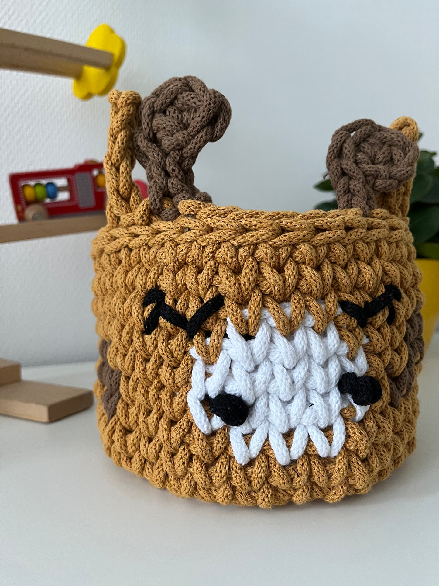 Handmade giraffe basket made from recycled cotton cord for toy storage in kids room.