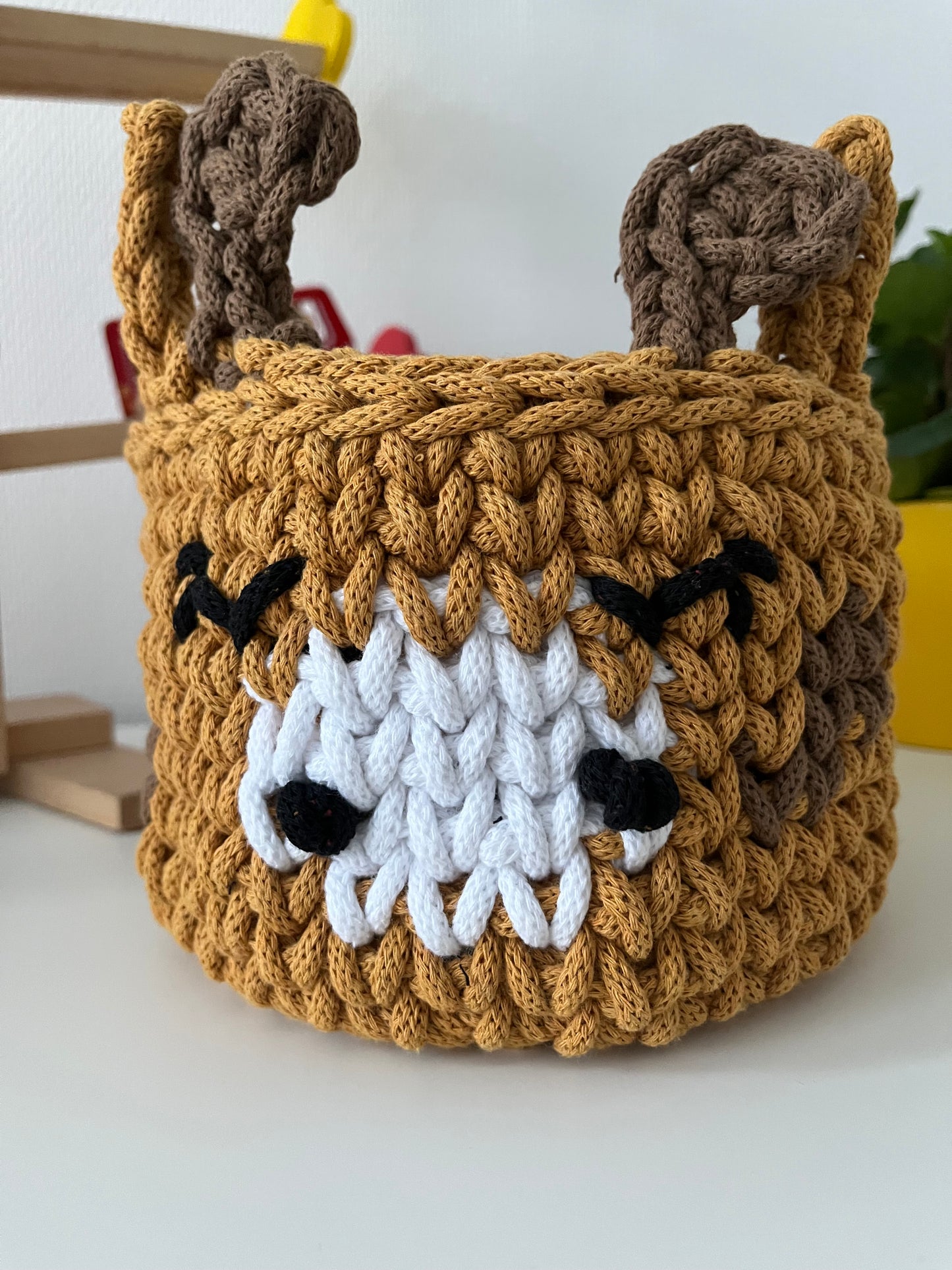 Handmade giraffe basket made from recycled cotton cord for toy storage in kids room.