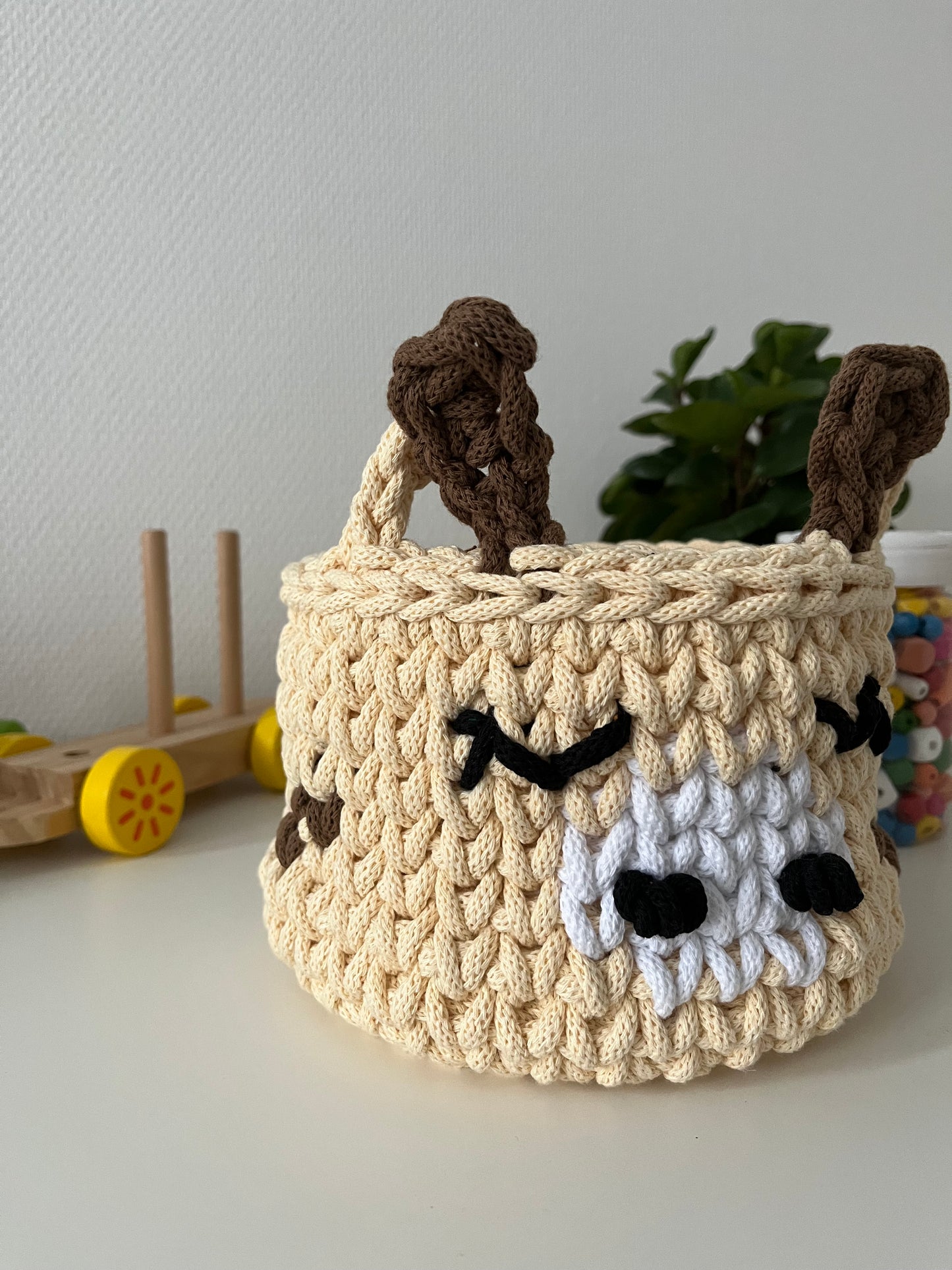 Handmade giraffe basket made from recycled cotton cord for toy storage in kids room.