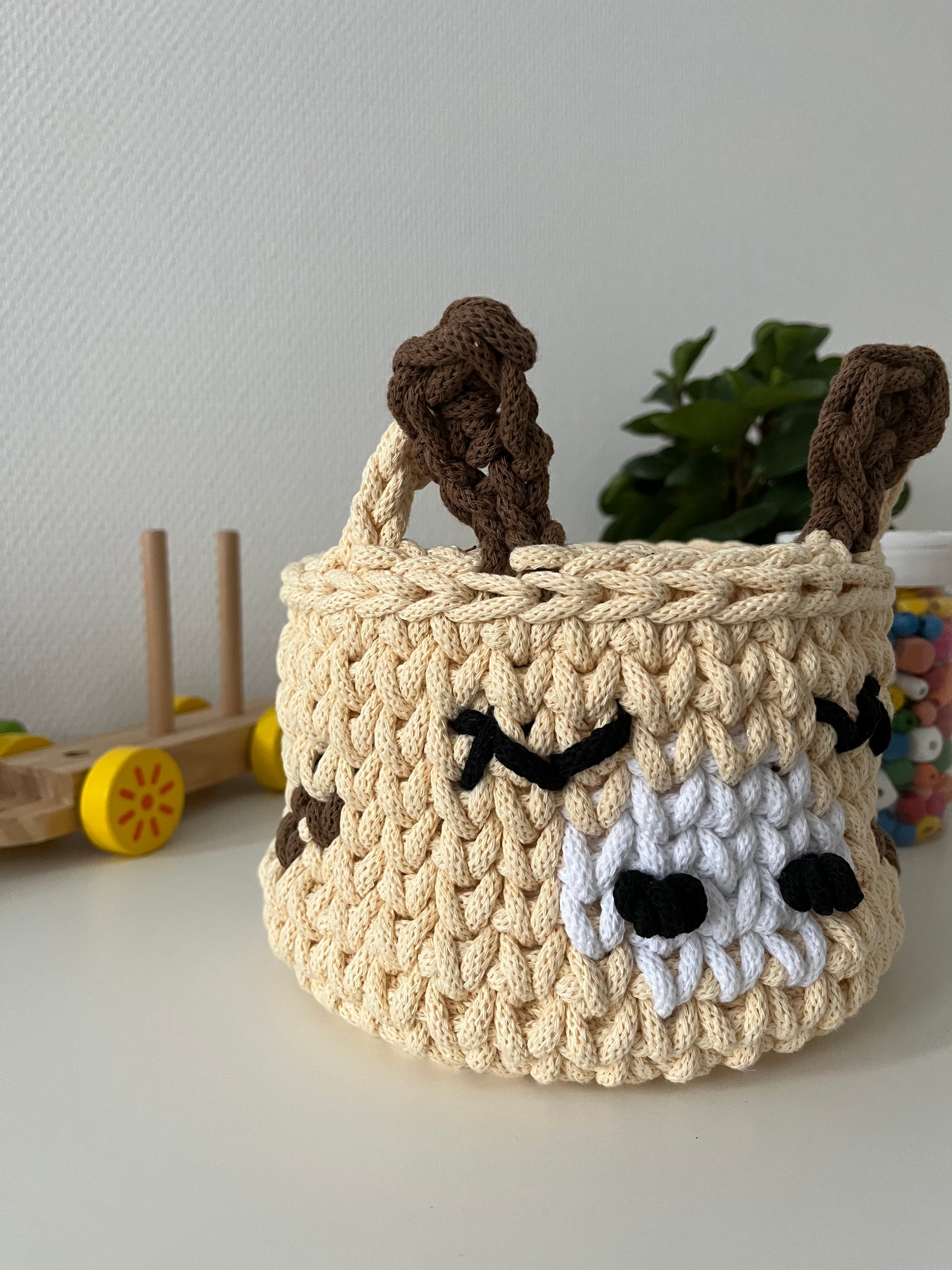 Handmade giraffe basket made from recycled cotton cord for toy storage in kids room.