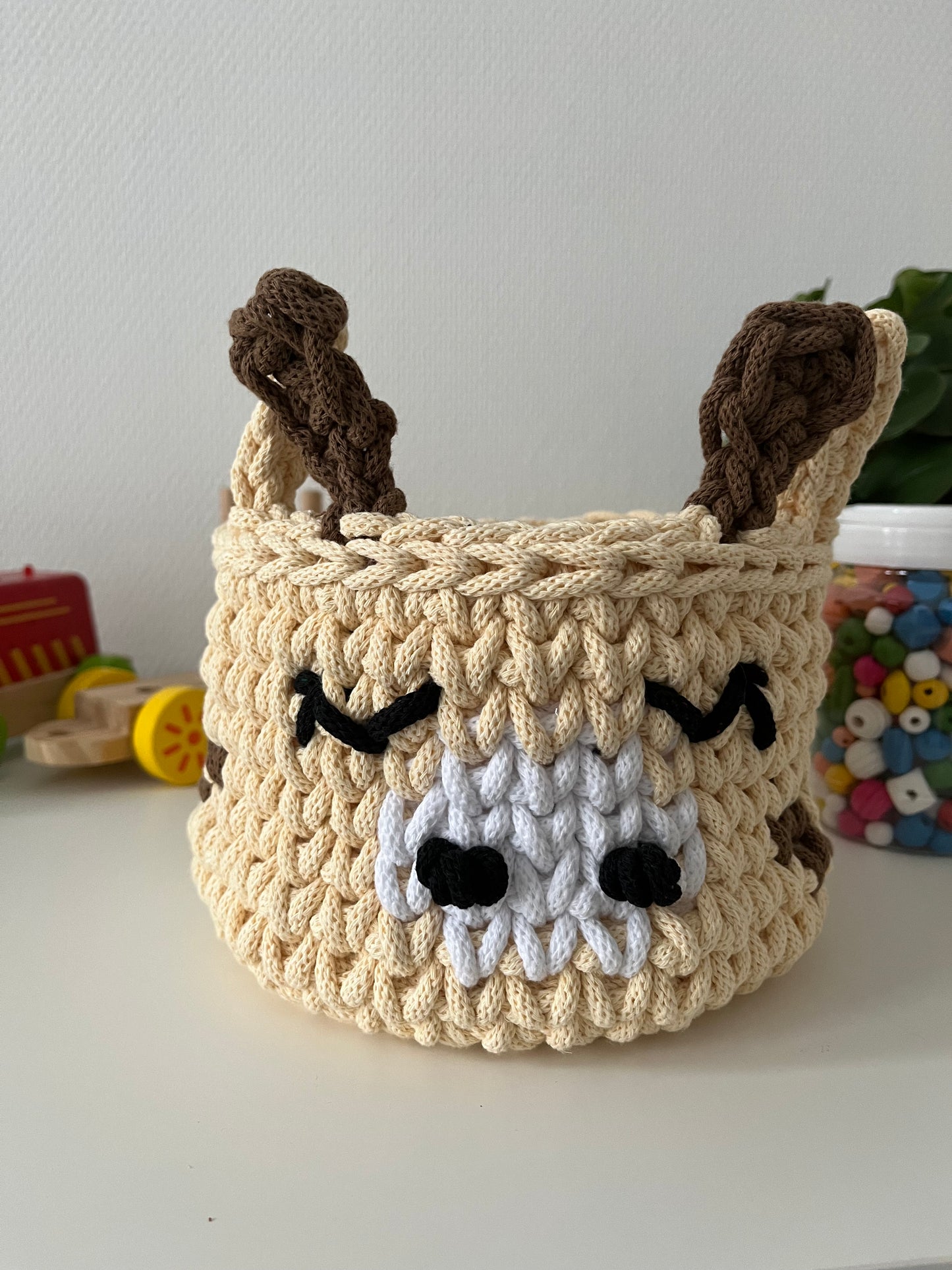 Handmade giraffe basket made from recycled cotton cord for toy storage in kids room.