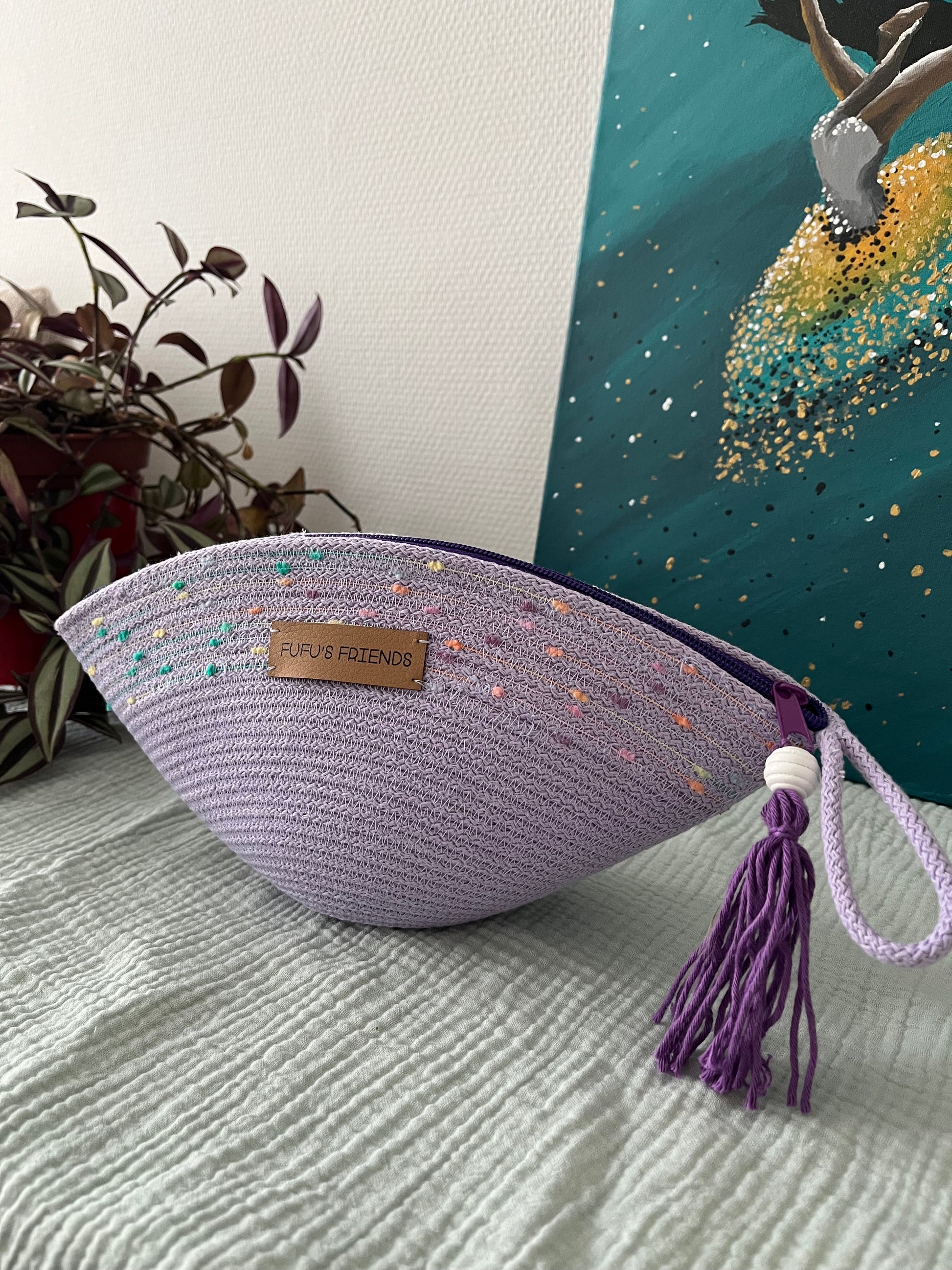 Handmade shell-shaped crochet pouch in pastel lavender with zipper closure.