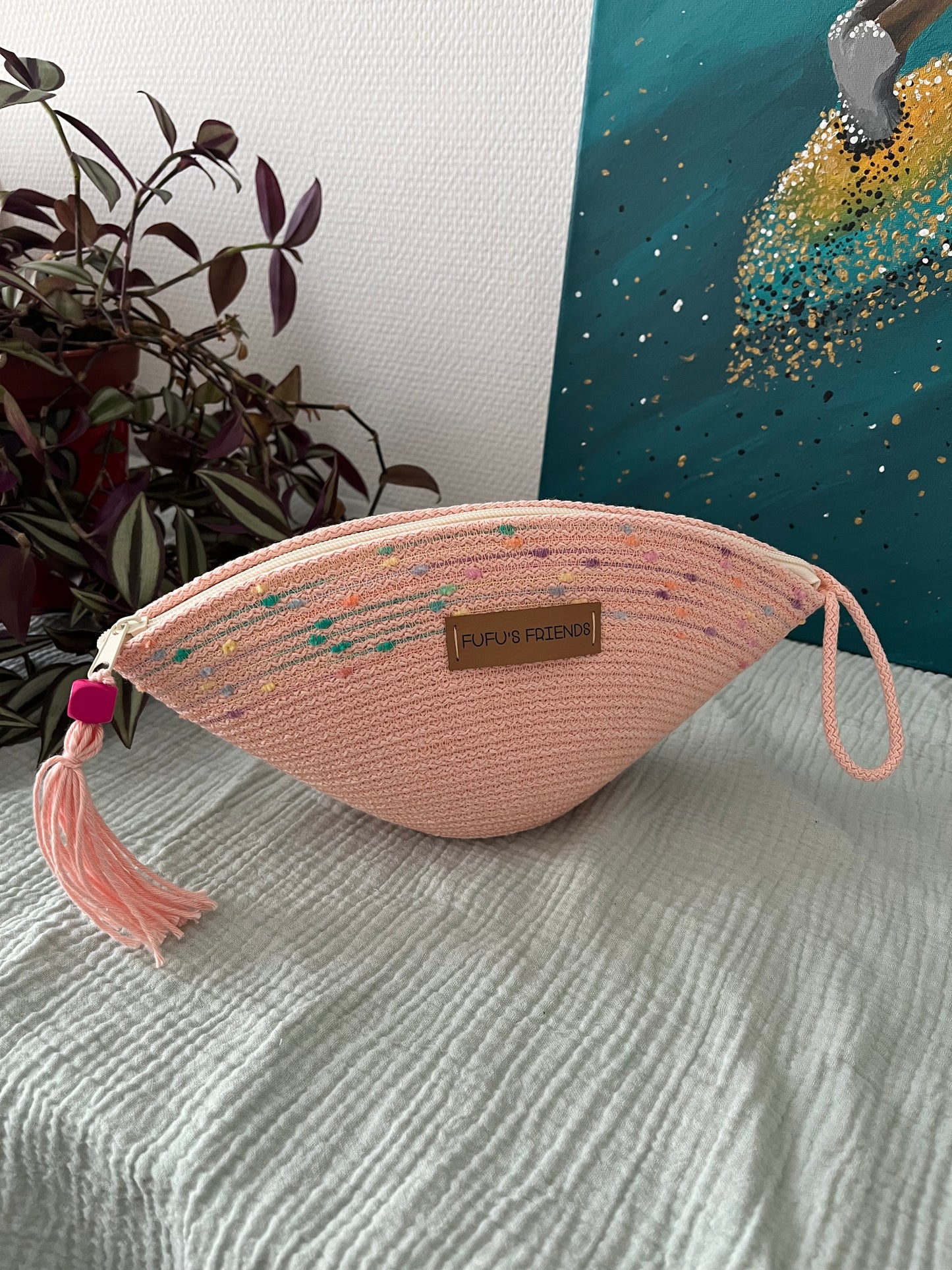 Handmade shell-shaped crochet pouch in soft pink with zipper closure.