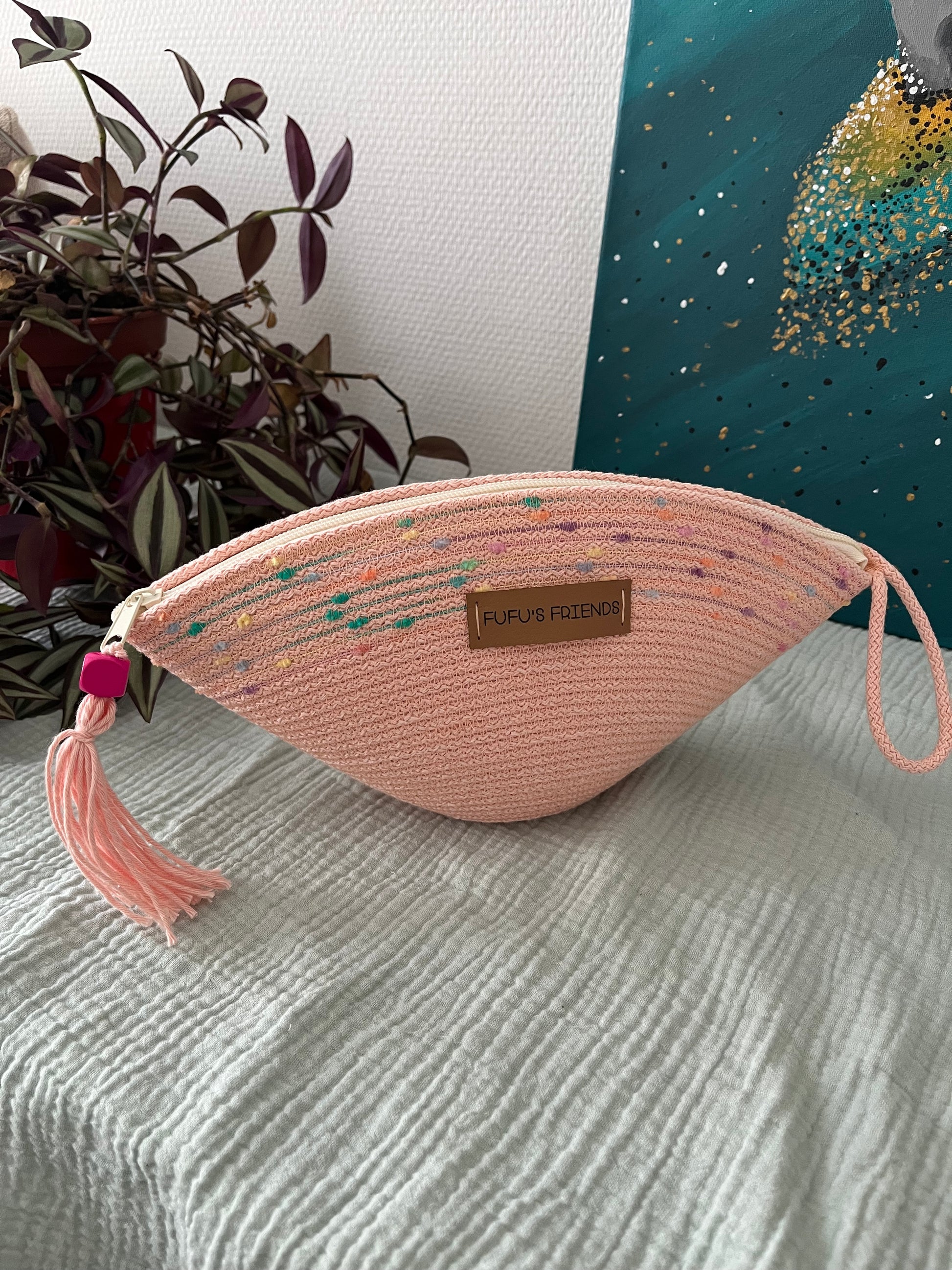Handmade shell-shaped crochet pouch in soft pink with zipper closure and tassel. 